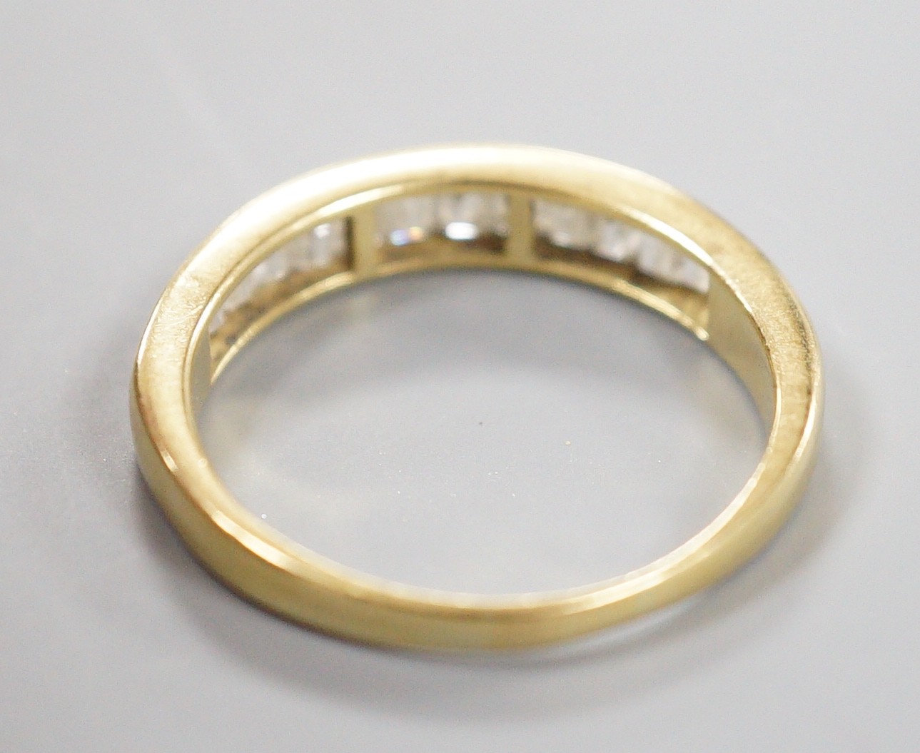 A modern 18ct gold and graduated baguette cut diamond set half eternity ring, size Q, gross 3.4 grams.